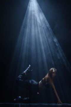 Mysterious silhouette of a female dancer under a blue spotlight beam. Concept of commercial template with copy space for musical show promo, theater poster and mental health therapy.