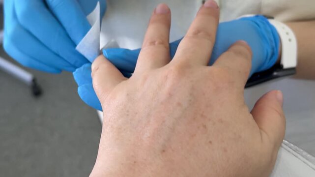 A nail technician gently cleans the client's nails with nail polish remover and a soft wipe, preparing a smooth surface for a fresh professional manicure. Close up.