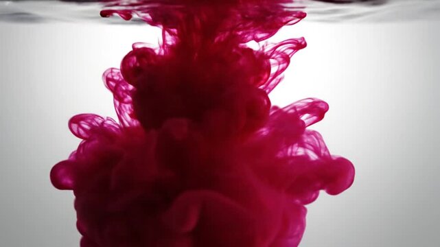 Single red drop falling into white liquid surface.