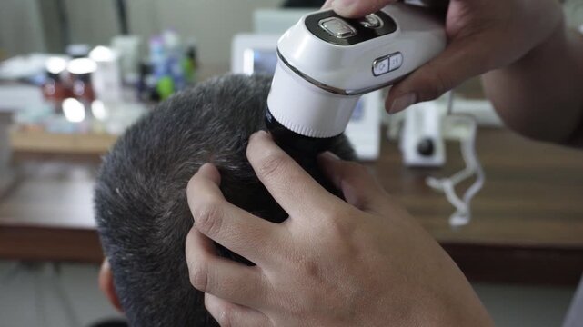 Close up of digital scalp analyzer examining a healthy middle aged man&rsquo;s scalp and hair follicles for scalp assessment and hair wellness monitoring.