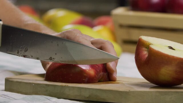Cook cutting up apple with sharp knife on board - closeup shot