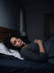 Fototapeta premium Indian woman patient lying awake in bed at night with bloodshot eyes. Sleeplessness and chronic insomnia health issues vertical banner with copy space