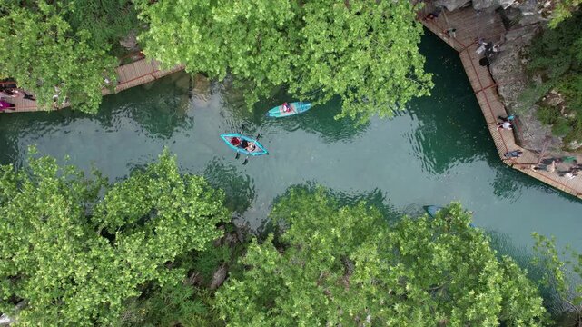 Andirin, Kahramanmaras, Turkey - 21 June 2026: Aerial view of people kayaking on the green river surrounded by lush trees and wooden walkways at Kanliboget.