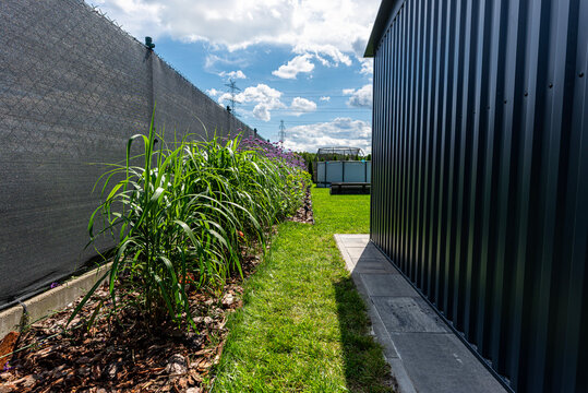 Modern sheet metal house with boundary fence and garden