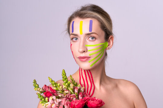 Close up of young woman with face and neck lifting tapes holding bouquet of flowers. Concept of aesthetics and innovative procedures