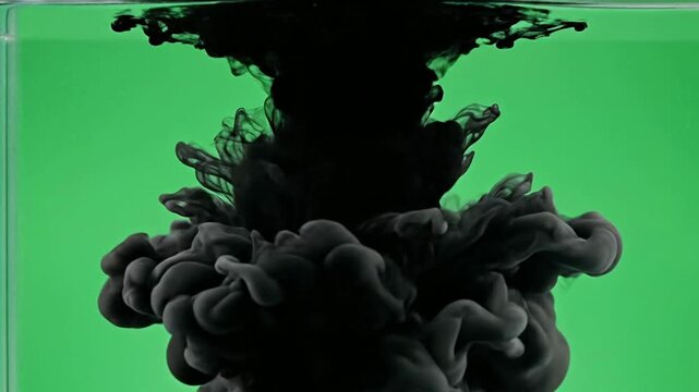 Black ink droplet swirling in water on green screen background, abstract liquid smoke motion for creative and visual effects