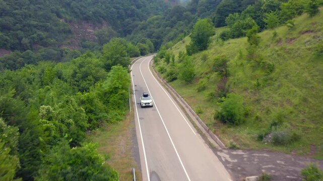 Car drives through elevated aerial view beside Zhinvali Reservoir and forested Georgian hills, supporting scenic road travel, transport planning, tourism promotion and regional mobility campaigns.