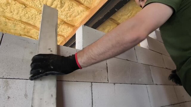 Professional builder laying aerated concrete blocks to construct interior partition walls inside a new residential building. Masonry work during house construction using lightweight gas concrete block