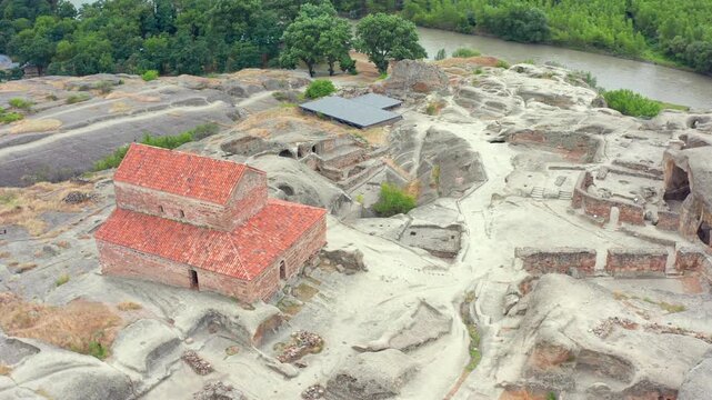Uplistsikhe church anchors overhead aerial view above carved paths, cave rooms and stone terraces near Gori, supporting religious heritage, archaeology mapping and Georgian tourism campaigns.