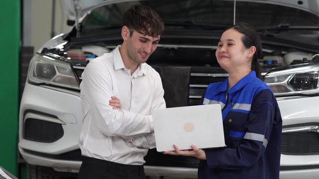 Car mechanic laptop inspection repair garage customer service diagnosis technician consultation, female technician reviews inspection report and vehicle diagnostics with male client near open hood