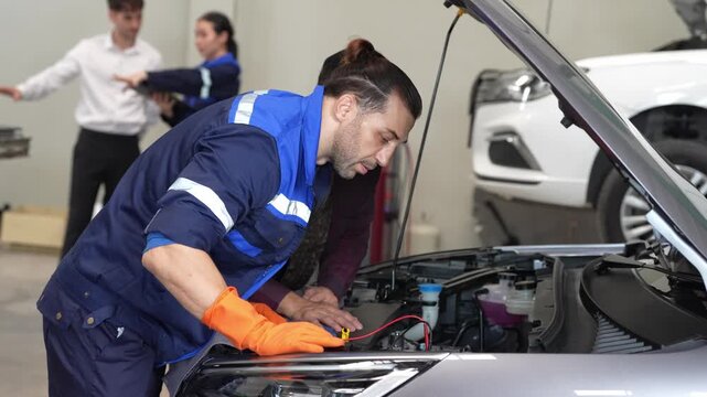 Mechanic car engine repair service diagnostic workshop glove technician performing maintenance inspection, checking vehicle battery and wiring with test lead open hood during auto garage routine