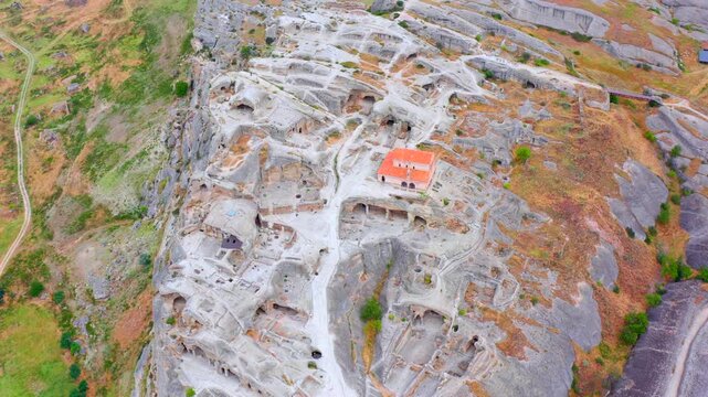 Uplistsikhe complex fills high aerial view above excavated caves, a hilltop church and surrounding roads, supporting regional geography, heritage tourism and archaeological site documentation.