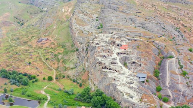 Uplistsikhe cave city fills elevated aerial view across ancient chambers, dry hills and visitor infrastructure near Gori, supporting destination marketing and archaeological tourism travel media.