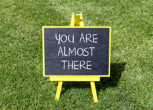 You are almost there words symbol. Concept words You are almost there on beautiful black blackboard. Beautiful grass background. Business You are almost there motivational support concept. Copy space.