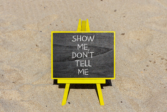 Tell or show symbol. Concept words Show me, do not tell me on beautiful black blackboard. Beautiful sand beach background. Business tell or show concept. Copy space.