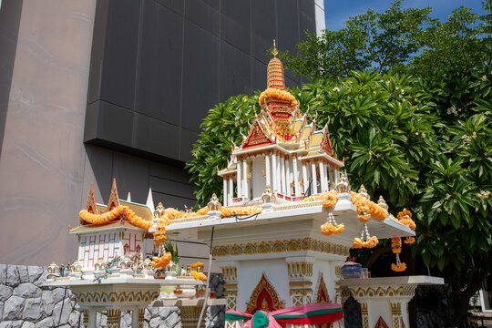 Traditional thai spirit house outdoor shrine decorated with yellow marigold flower garlands and offerings