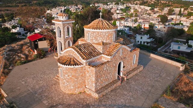 Aerial view of Profitis Elias Church in Protaras, Cyprus. The stone church, domed roof and small courtyard are seen from above in warm evening light.