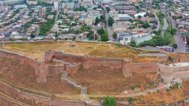 Aerial drone orbits above Gori Fortress in Georgia, mapping the oval citadel, stone ramparts and dense city blocks for archaeology, preservation, urban planning and historical documentary use.