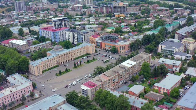 Central Gori fills circling aerial view above the main square, public buildings and dense neighborhoods, supporting civic tourism, municipal planning, local economy and Georgian destination marketing.