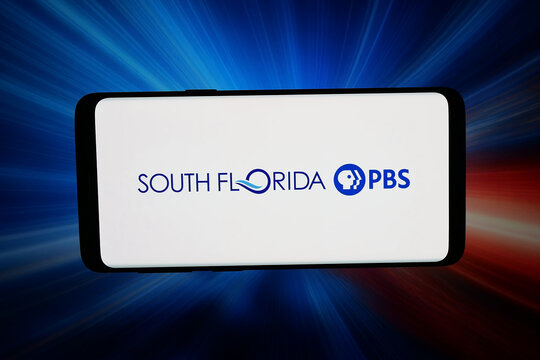 Stuttgart, Germany - 07-20-2026: In this photo illustration, the logo of US public TV company South Florida PBS Inc. is displayed on a smartphone in front of abstract background on computer screen.