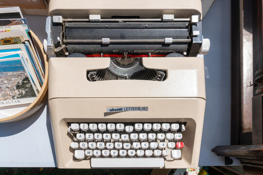 Haguenau, France &ndash; June 14, 2026: A classic Olivetti Lettera 35 portable typewriter with AZERTY keyboard displayed for sale at an outdoor flea market alongside vintage postcards and collectibles, high