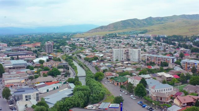 Drone moves sideways across Gori in Georgia, revealing broad avenues, residential blocks and mountain surroundings for urban tourism, city planning, regional development and property media use.