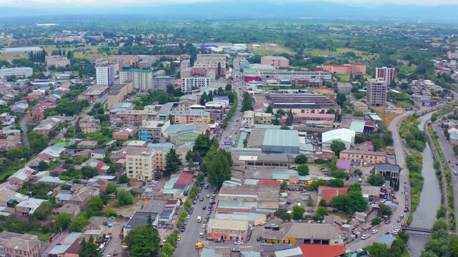 Drone flies forward above central Gori in Georgia, crossing commercial streets, residential neighborhoods and civic buildings for urban development, business location, planning and city tourism media.