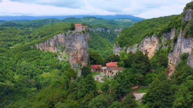 Katskhi Pillar dominates aerial view above the monastery complex and deep green canyon in Imereti, supporting Orthodox heritage, cultural tourism, architecture media and landmark media promotion.