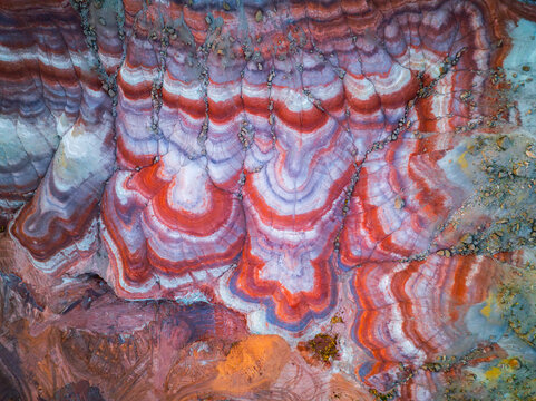 Aerial view of the vibrant, multi-colored bentonite hills with distinct red, white, and purple sedimentary layers and eroded terrain in Hanksville, Utah, United States.