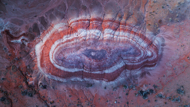Aerial view of the colorful striped badlands formations with distinct red, white, and purple sedimentary layers in the desert landscape near Hanksville, Utah, United States.