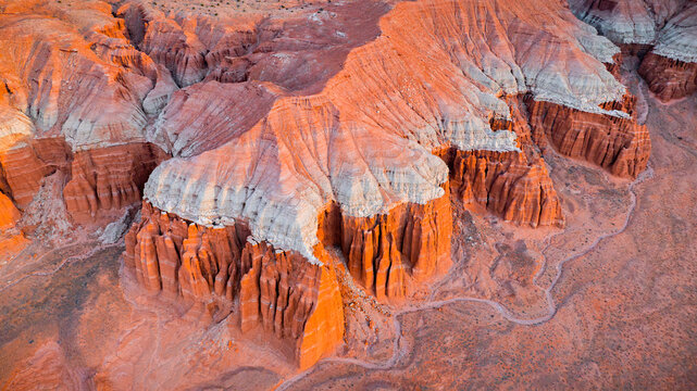 Aerial view of the striking red rock badlands with layered sandstone formations, deep canyons, and rugged terrain in Hanksville, Utah, United States.