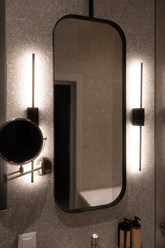 Modern bathroom interior featuring an oblong mirror with integrated led lighting on a speckled wall. Creating a clean. Bright