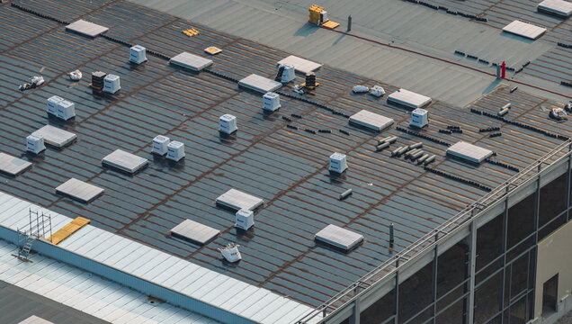 Loriol-sur-Drome, France - 26 July 2026: Aerial view of a modern industrial warehouse under construction, featuring roofing works with skylights, waterproofing membrane, and insulation materials.