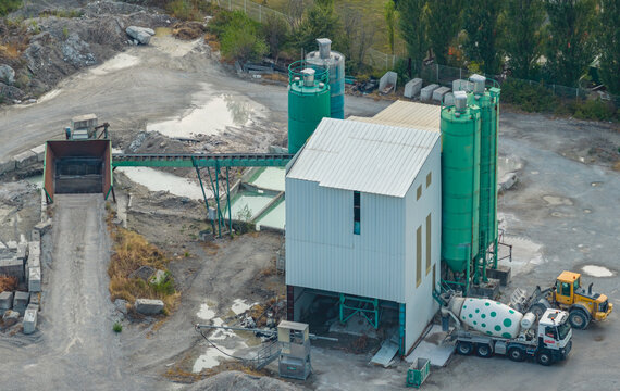 Loriol-sur-Drome, France - 26 July 2026: Aerial view of a concrete batching plant with aggregate conveyor, storage silos and a mixer truck in an industrial facility.