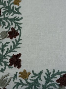 Elegant hand-stitched floral embroidery adorns a soft linen fabric creating a rustic and timeless textile pattern