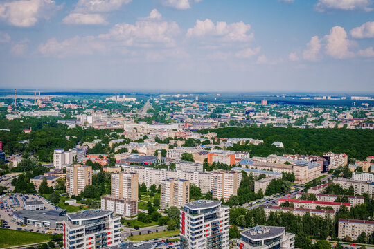 Riga, Latvia - 25 May 2014: Aerial view of modern residential district Skanste and Riga city skyline with apartment buildings, green trees, and urban infrastructure under a blue sky.