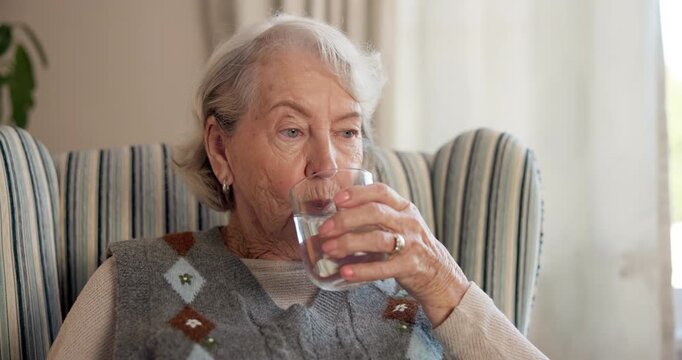 Old woman, drinking water and relax with glass in home, nutrition and digestion with liquid mineral. Retirement, wellness and elderly person with beverage for hydration, thirsty and detox in house