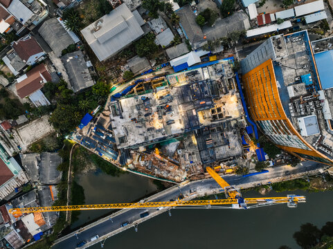 Kecamatan Cipayung, Indonesia - 24 July 2026: Aerial view of the Bambu Apus construction site featuring a large yellow crane, concrete structures, and surrounding urban rooftops.