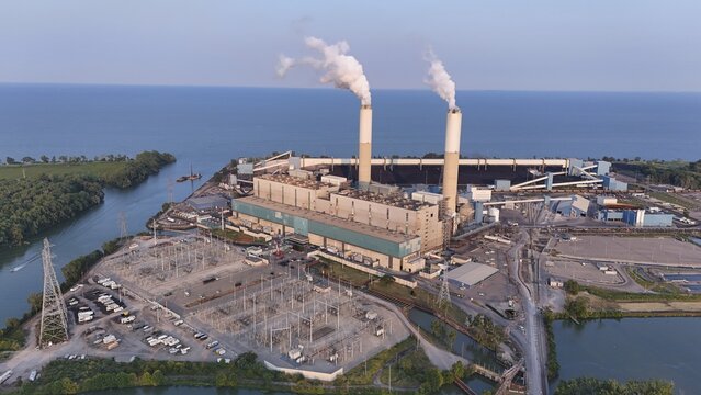Monroe, Michigan, United States - 25 July 2026: Aerial view of DTE Energy Monroe Power Plant with two tall chimneys emitting smoke, situated on the shore of Lake Erie.