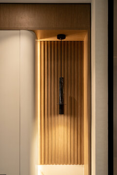Modern black marble pendant light fixture in a fluted wooden wall alcove.