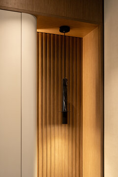 Modern black marble pendant light fixture in a fluted wooden wall alcove.
