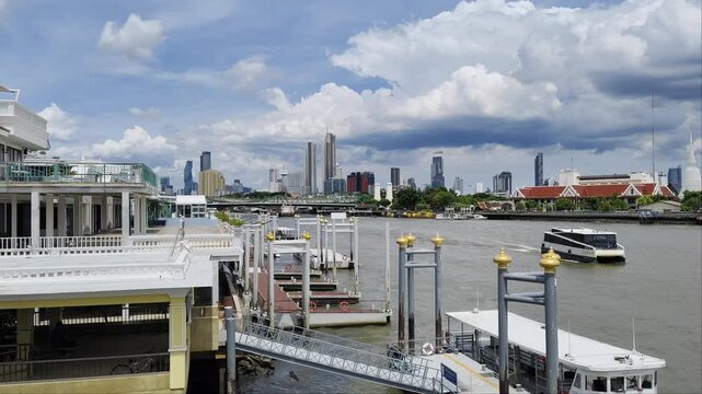 Chao Phraya Express Boat arriving at Rajini Pier in Bangkok, Thailand, showing the floating pontoon dock, gangway, and urban river transport during the day.
