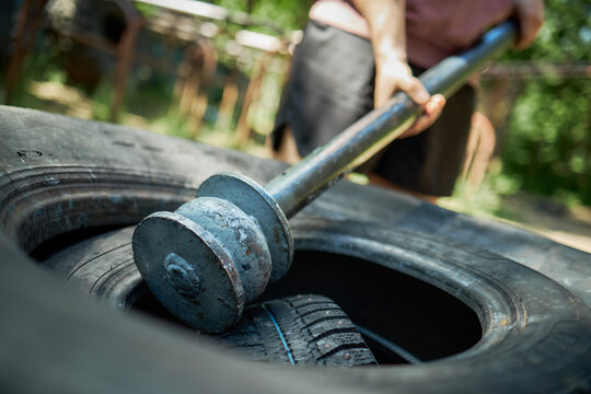 Close up of young adult athlete lifting barbell over stacked tires, training outdoors for strength and endurance. Suitable for fitness promotion, bootcamp ads, workout branding