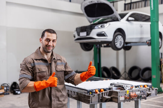 Confident EV Technician Giving Thumbs Up After Successful High Voltage Battery Repair in Electric Vehicle Service Center