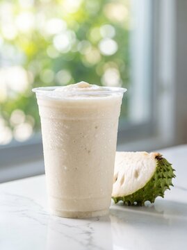 Creamy soursop smoothie in clear takeaway cup served with fresh soursop fruit slice
