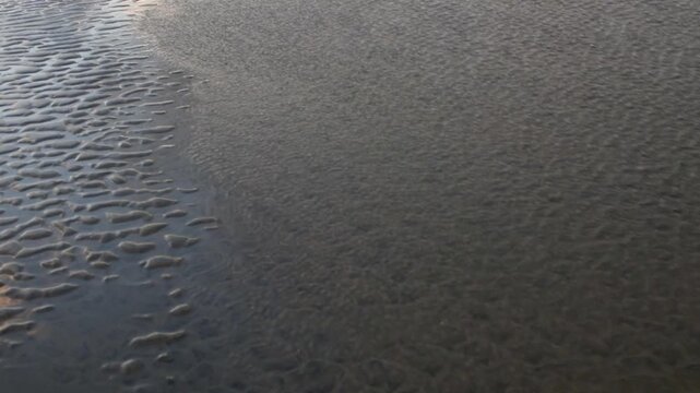 Beautiful abstract sand art peaceful background from the changing of the tide of the ocean at the beach