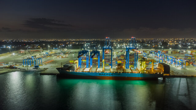 Accra, Ghana - 25 July 2021: Aerial view of MPS Terminal 3 at the port of Accra, featuring a large Maersk container ship being unloaded by cranes under the night sky.