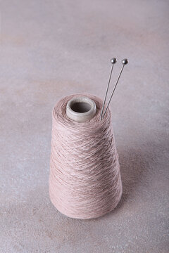 Wool yarn for knitting or crocheting. Metal knitting needles for hand knitting. Yarn on a spool. Fine, pure wool yarn in a fine, light color. Copy space. Hobby and craft concept