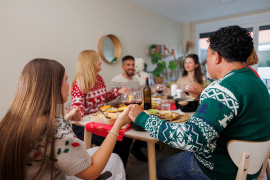 Family holding hands praying at christmas dinner table