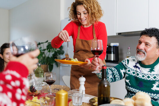 Woman serving christmas dinner toasting family and friends